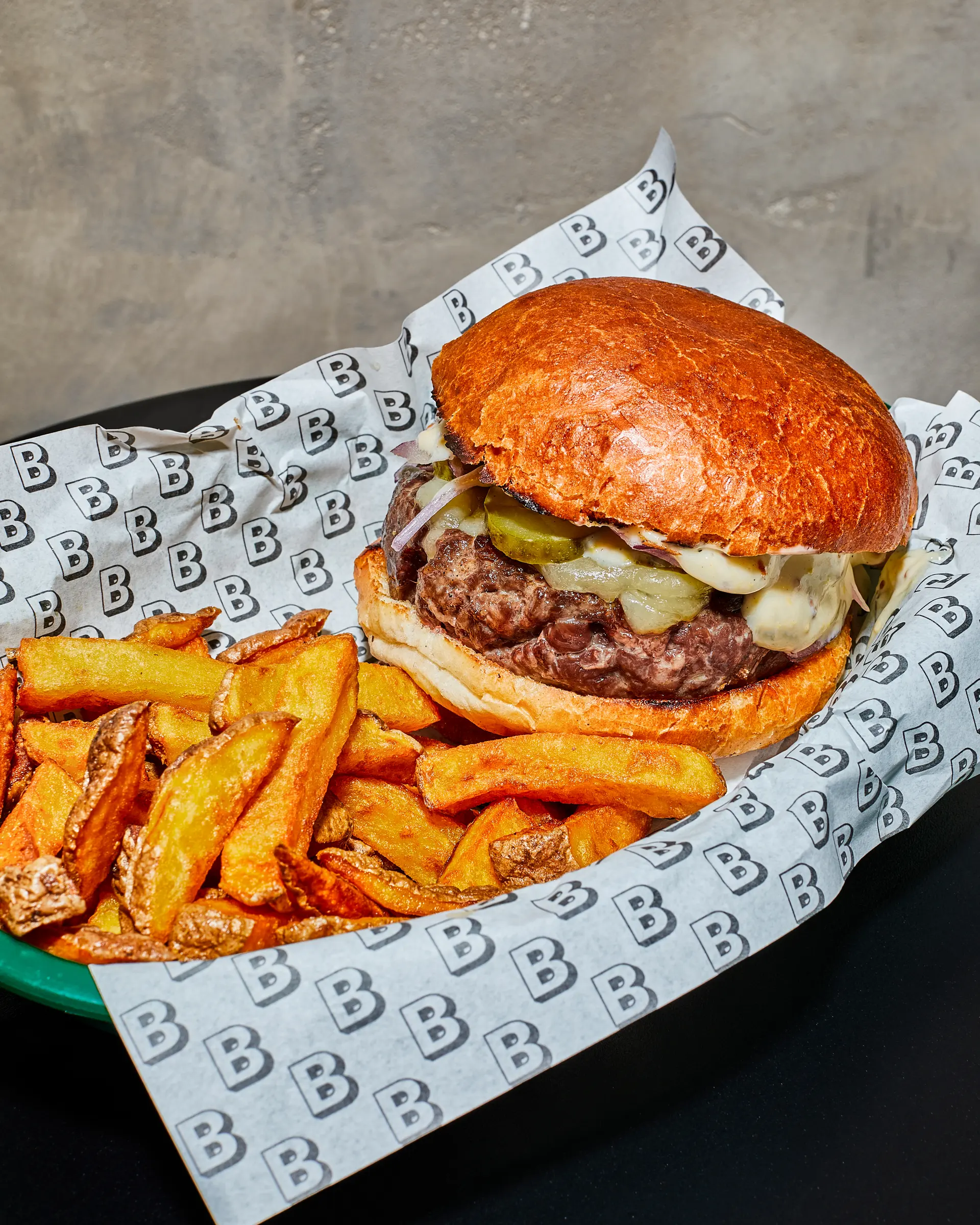 Hovězí burger s nakládanými okurkami a hranolkami v Bufetu.