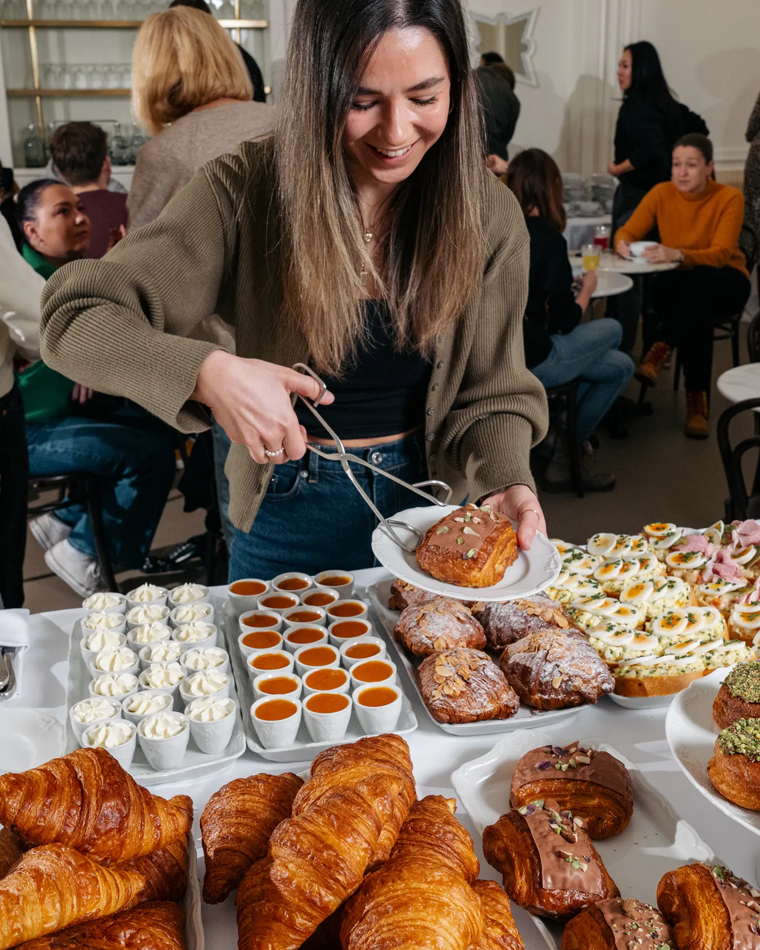 Žena si nabírá sladké pečivo a dezerty z brunchového bufetu v kavárně.