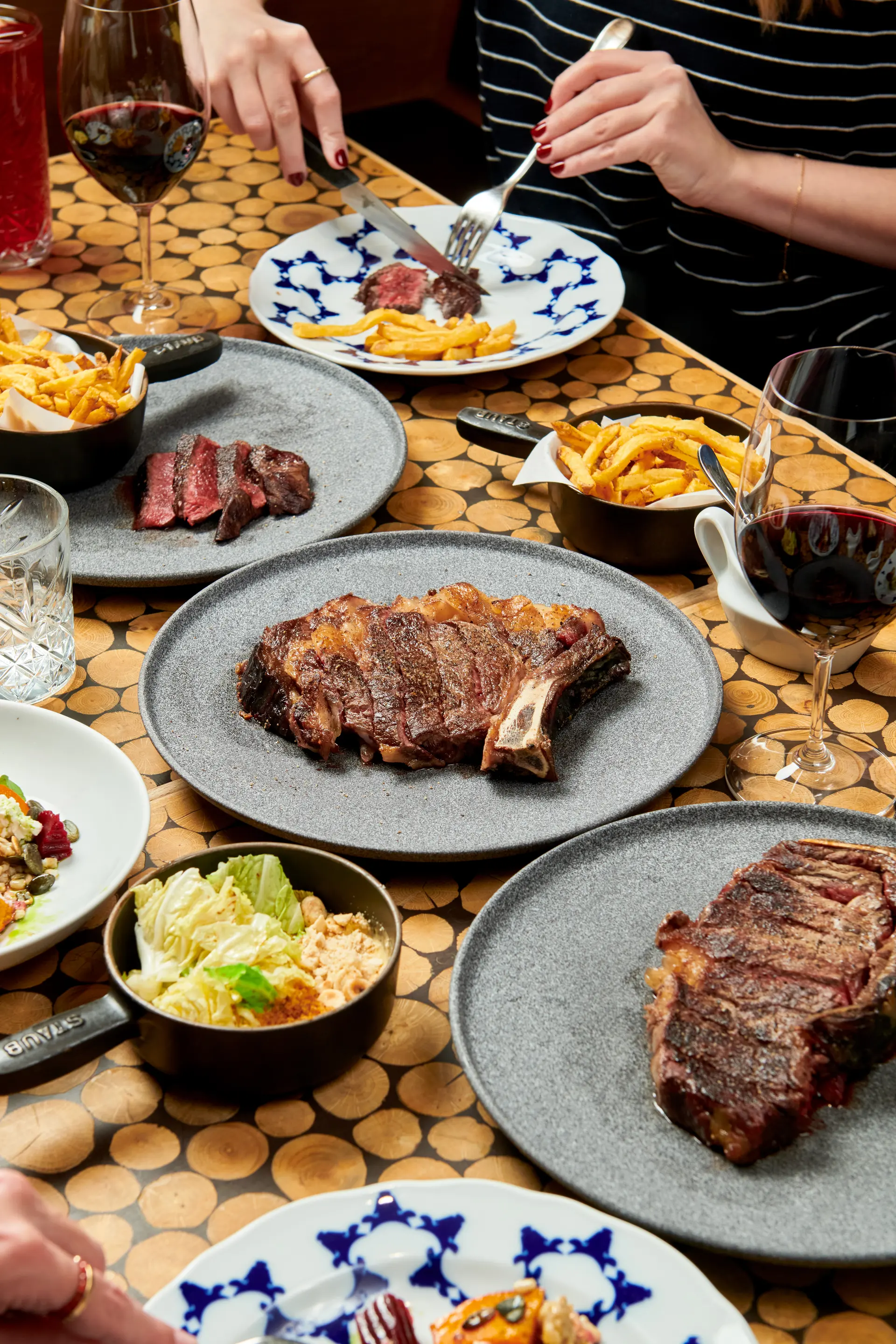 Hovězí steaky s hranolky a přílohami na stole v restauraci Čestr.