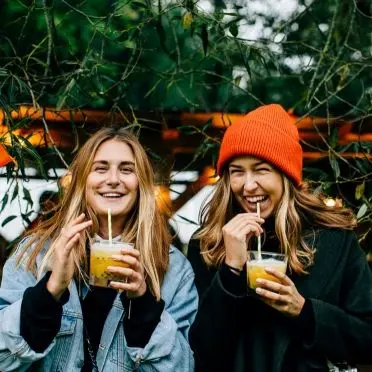 Two young women drinking a cocktail.