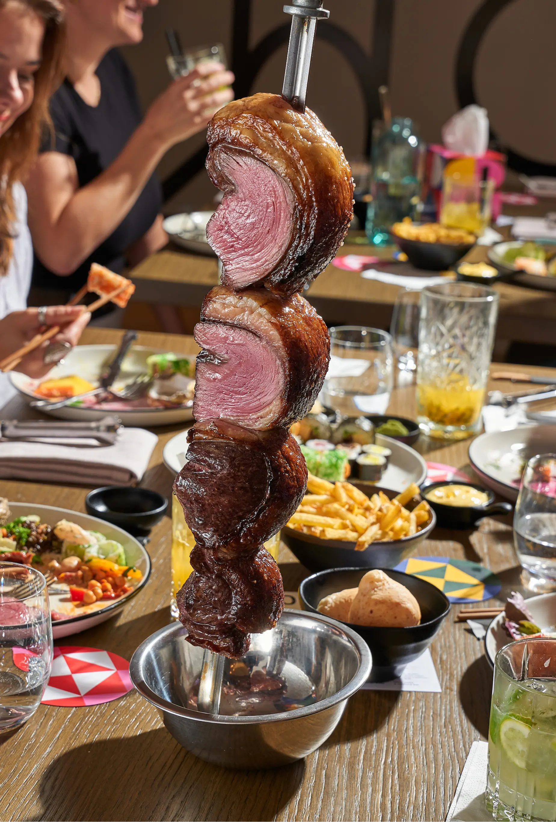 Hovězí maso churrasco servírované na jehle při stolování v restauraci Brasileiro.