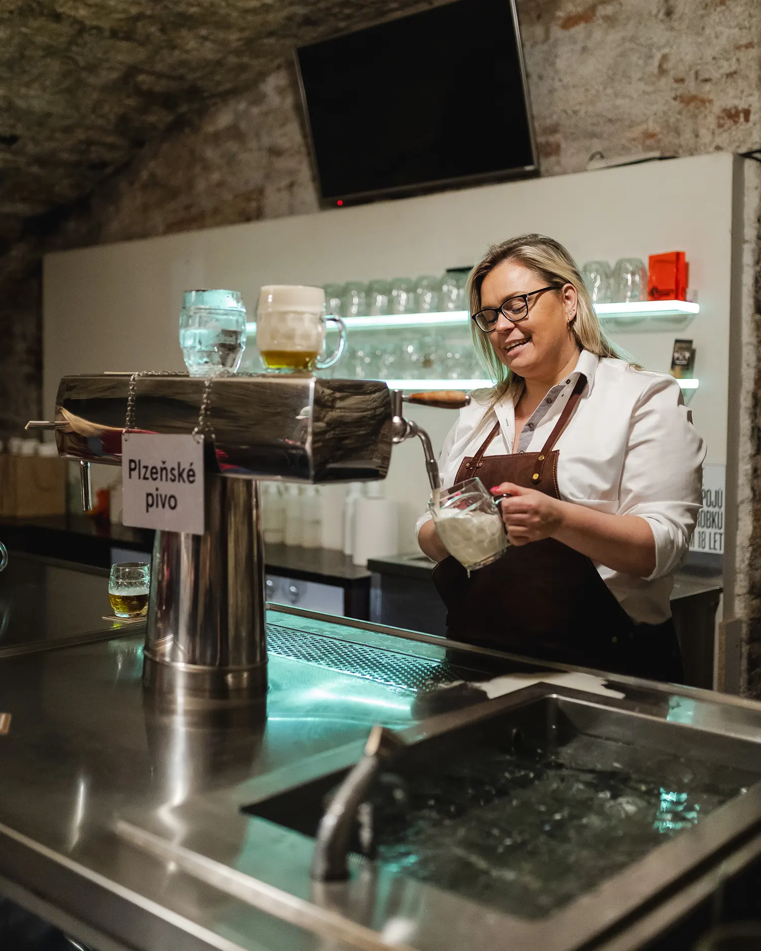 Bartender pouring Pilsner beer at the bar in an Ambiente restaurant.