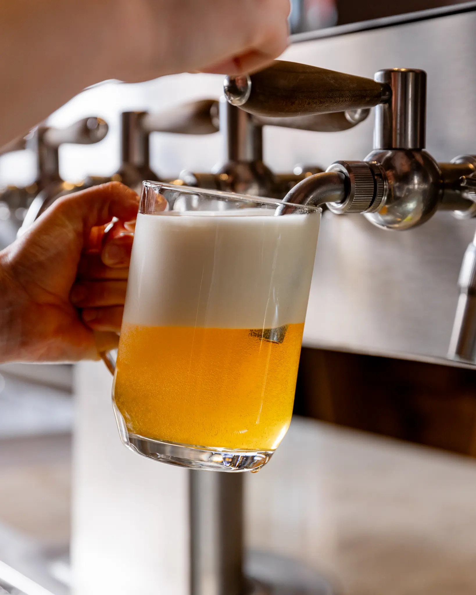 Čepování čerstvého piva do sklenice v Pultu, detail pivního kohoutu a pěny.