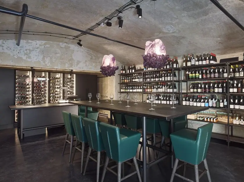 Interiér obchodu s vínem Vin de Marie s degustačním stolem a vinotékou.