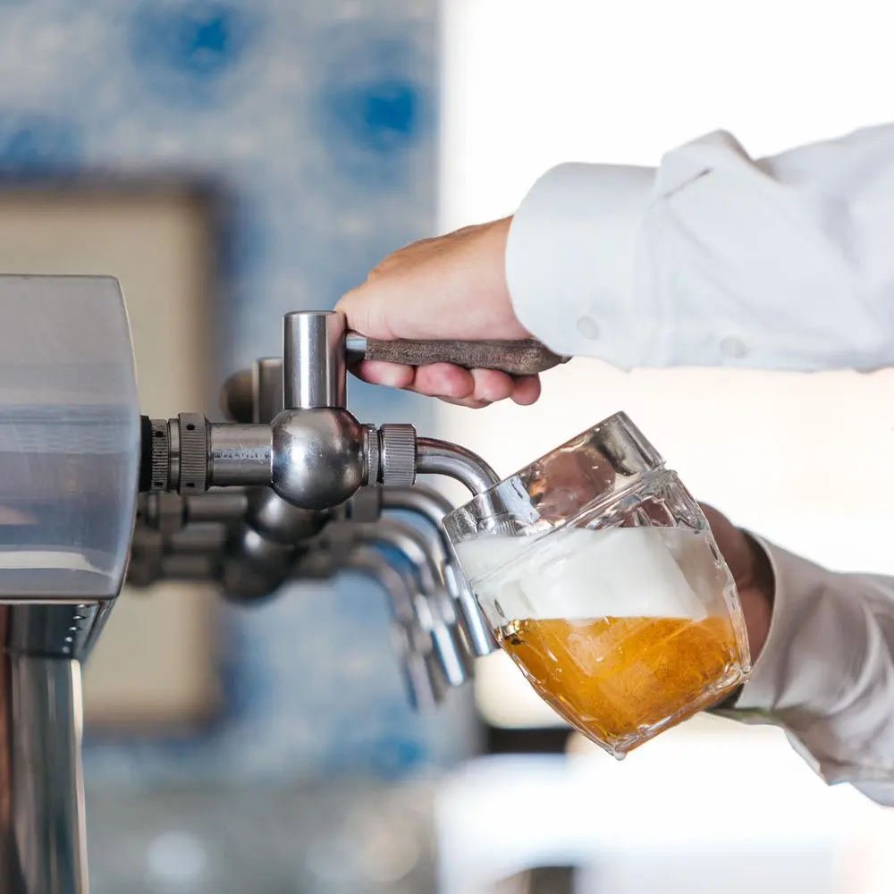 Pouring beer into a tilted glass under a draft tap.